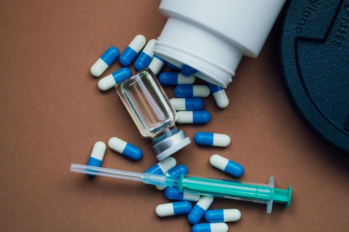 A collection of steroids spread out on the ground with a dumbbell.